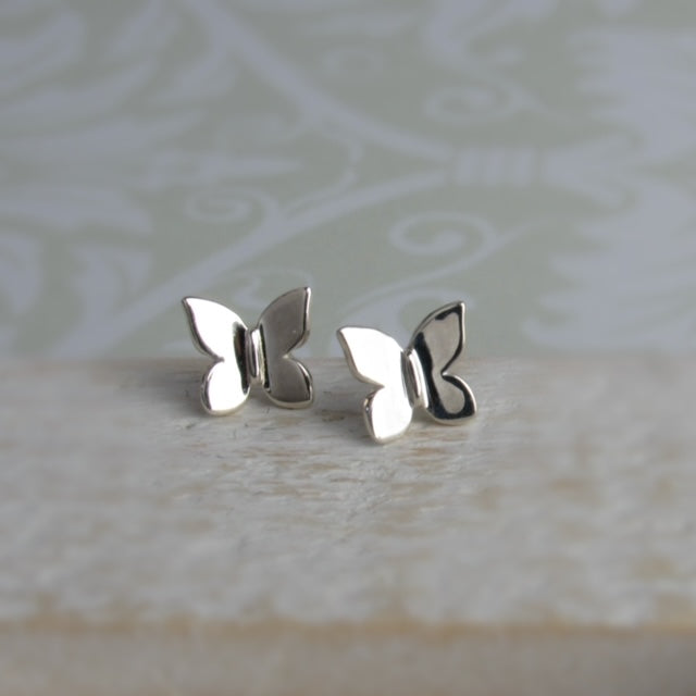 Silver butterfly earrings on a textured surface