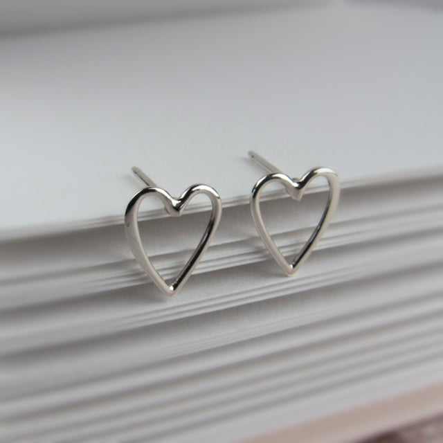 Silver heart-shaped earrings on a book