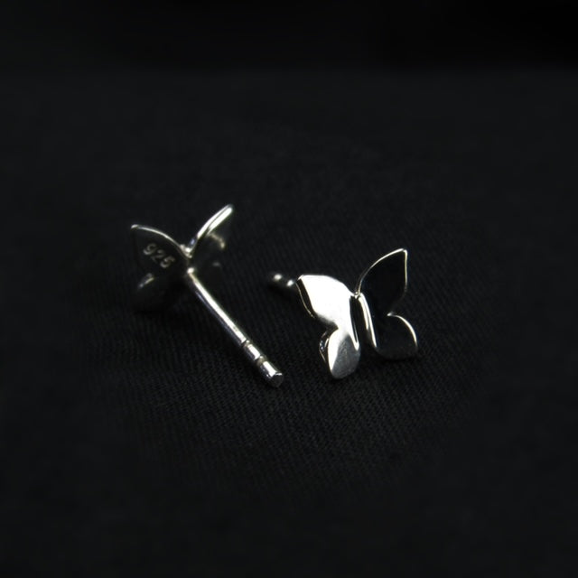 Silver butterfly earrings on a black background