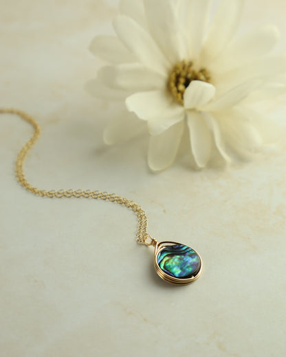 Gold necklace with a colorful pendant on a light background