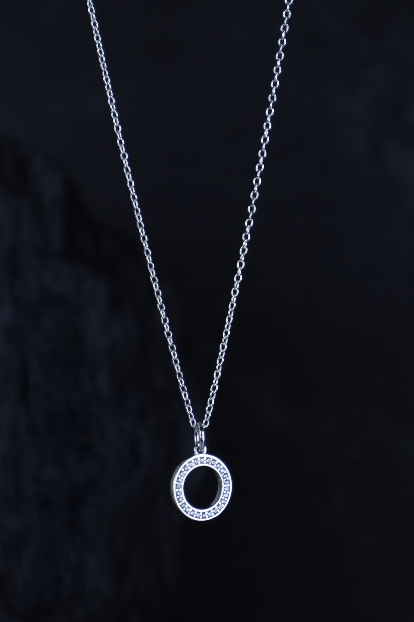 Silver necklace with a circular pendant on a dark background