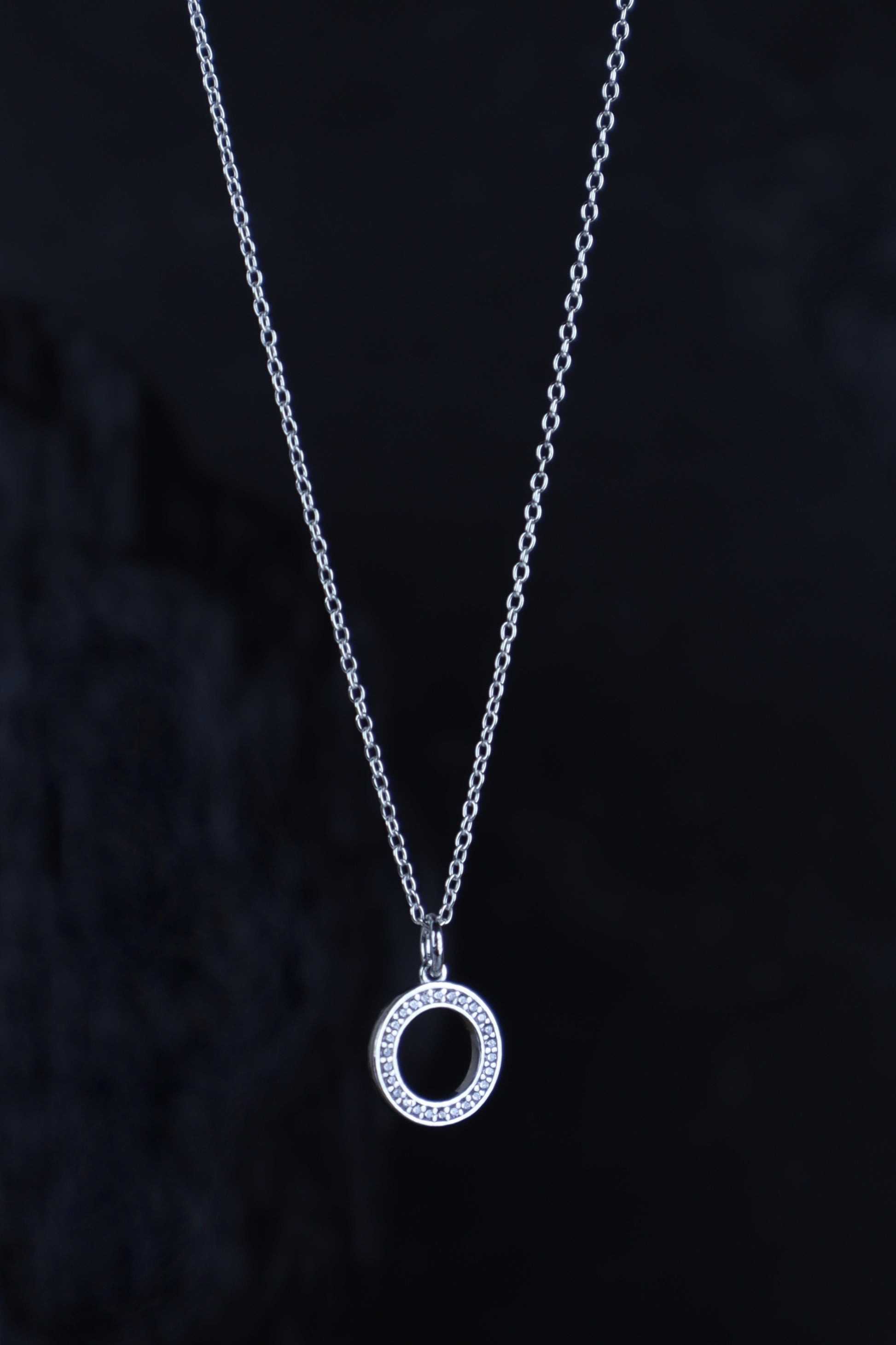Silver necklace with a circular pendant on a dark background
