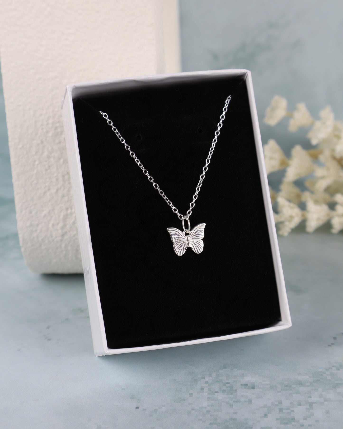 butterfly pendant necklace on a black insert in a white box close up