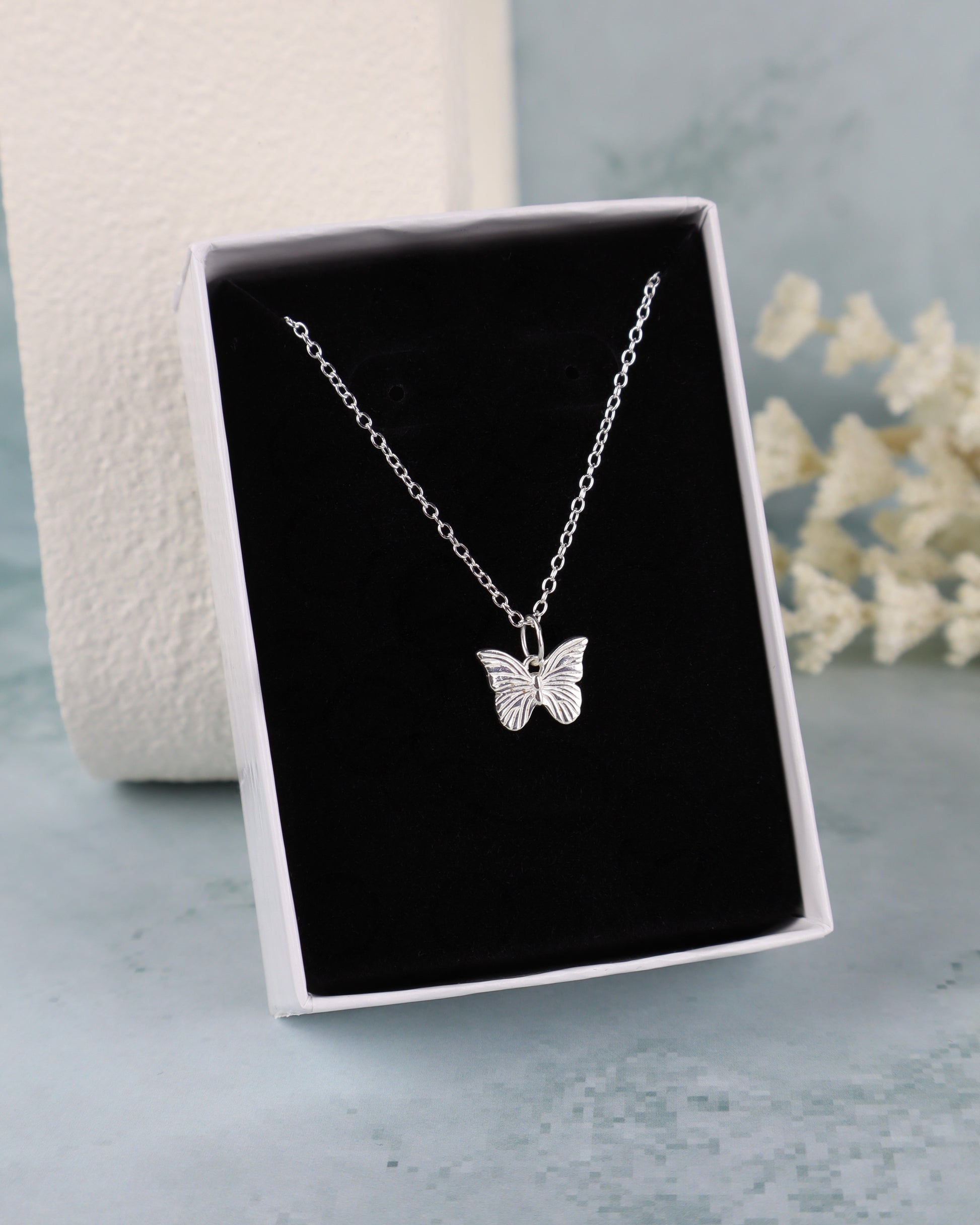 butterfly pendant necklace on a black insert in a white box close up