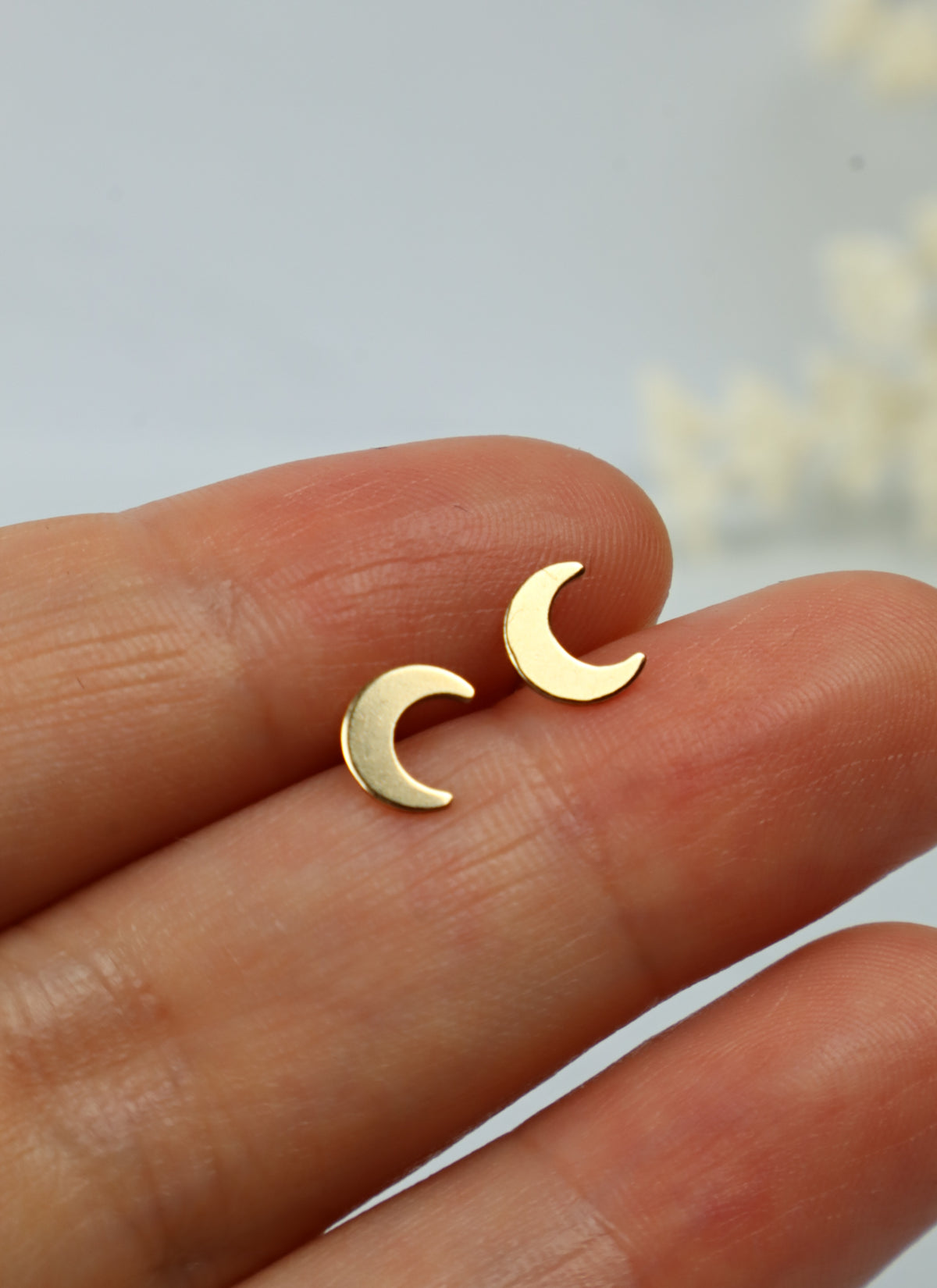 gold moon earring studs being held
