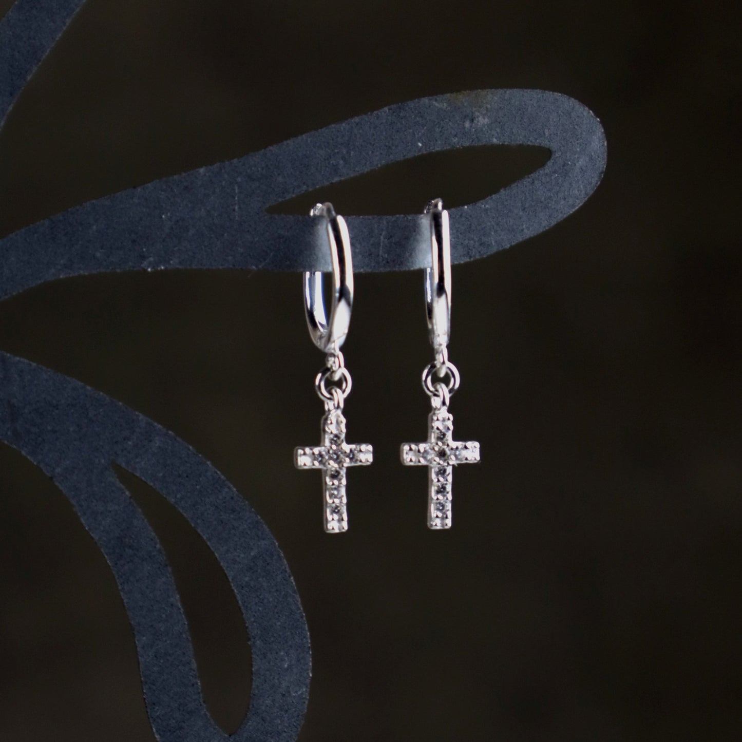 Sterling Silver cross huggie earrings on a dark background
