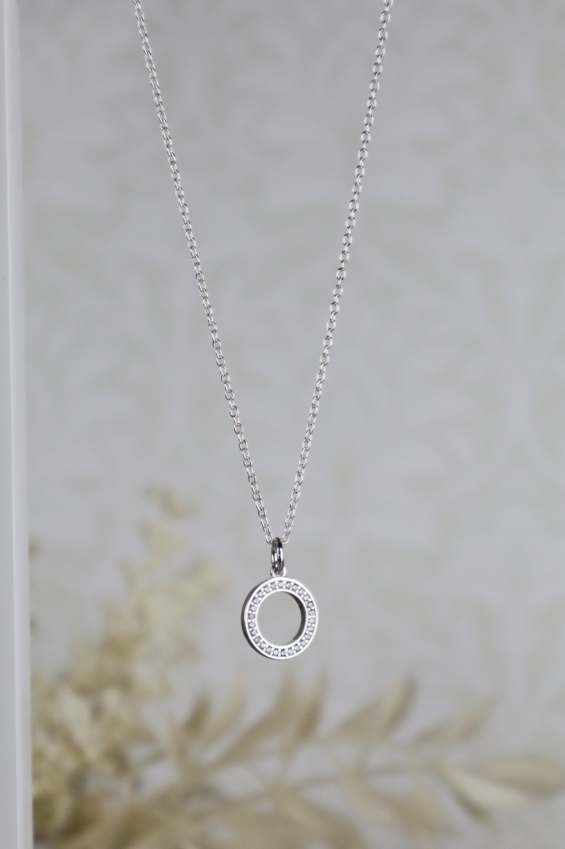 Silver necklace with a circular pendant on a neutral background