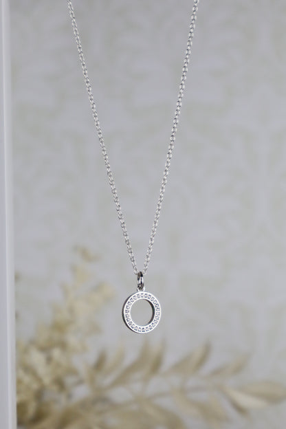 Silver necklace with a circular pendant on a neutral background