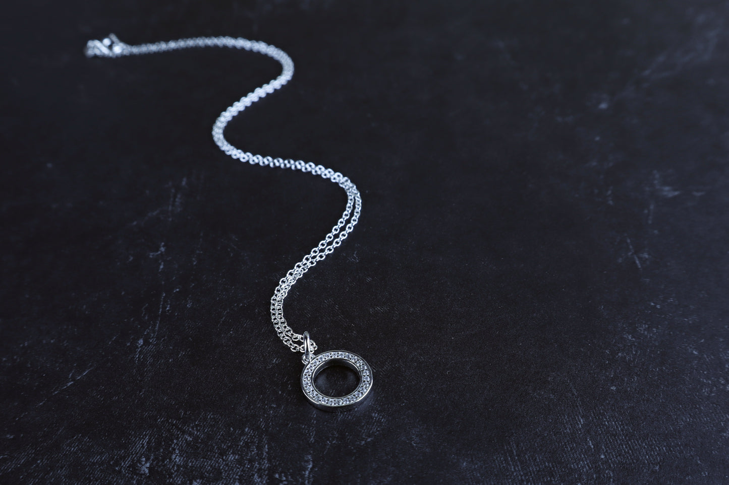 Silver necklace with a pendant on a dark textured surface