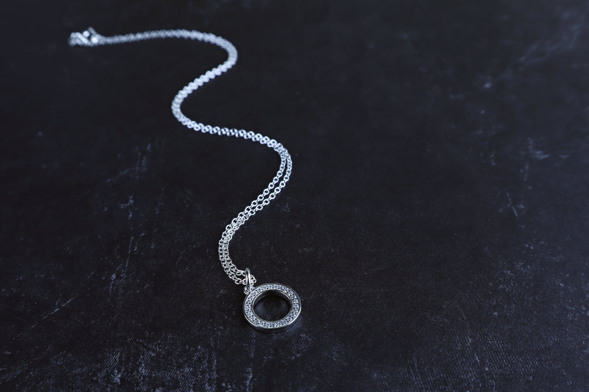 Silver necklace with a pendant on a dark textured surface