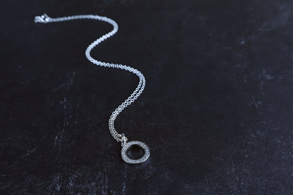 Silver necklace with a pendant on a dark textured surface