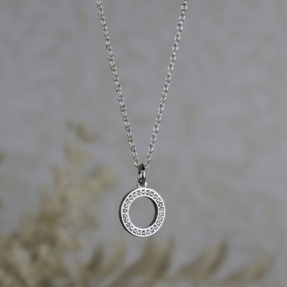 Silver necklace with a circular pendant on a blurred background