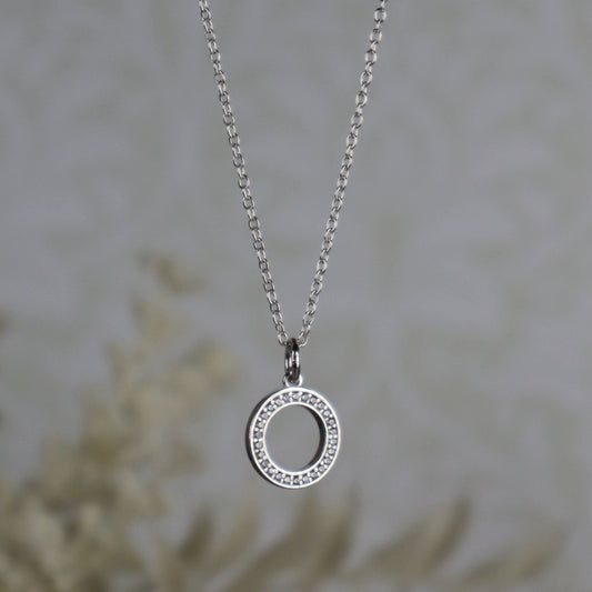 Silver necklace with a circular pendant on a blurred background