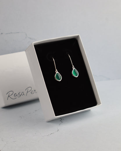 Green teardrop earrings in a 'Rosa Per' jewelry box on a light gray background