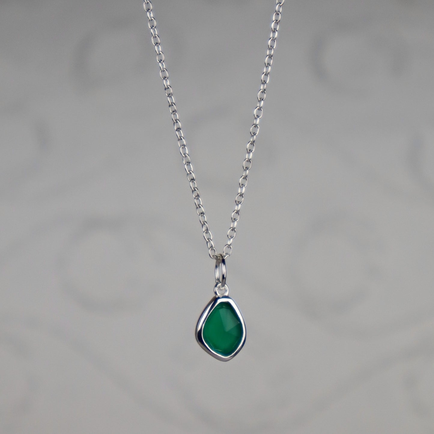 Necklace with a green teardrop pendant on a gray background