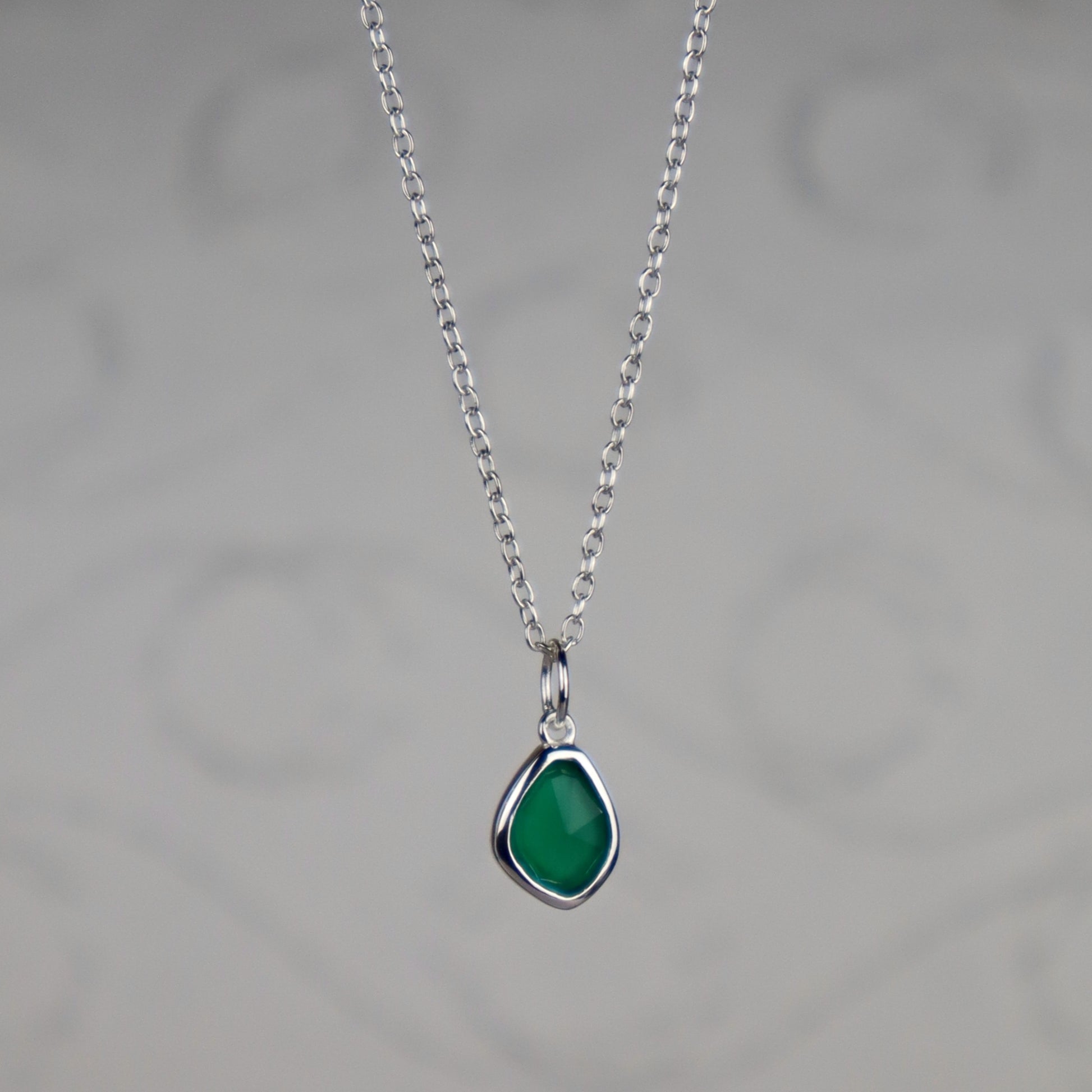 Necklace with a green teardrop pendant on a gray background