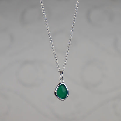 Necklace with a green teardrop pendant on a gray background
