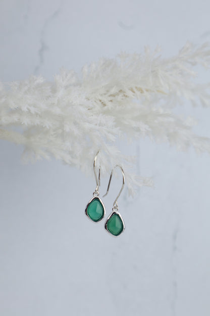 Teardrop-shaped green earrings on a light background
