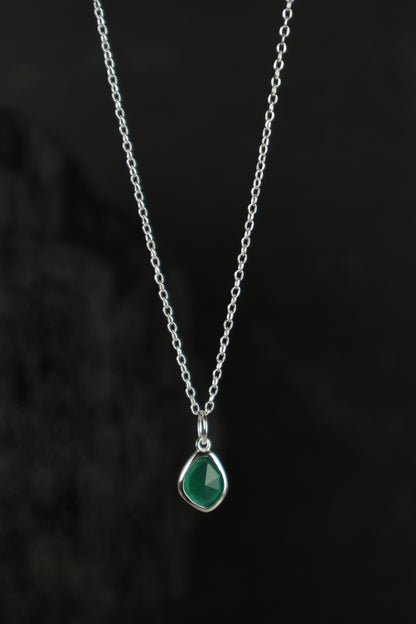 Necklace with a green teardrop pendant on a dark background