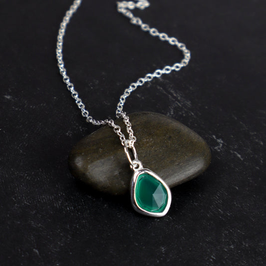 Necklace with a green teardrop pendant on a dark stone surface