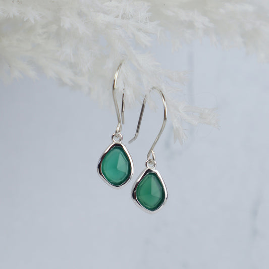 Teardrop-shaped green earrings on a light gray background