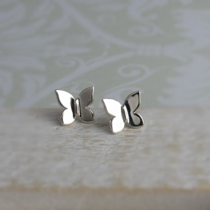 Silver butterfly earrings on a textured surface