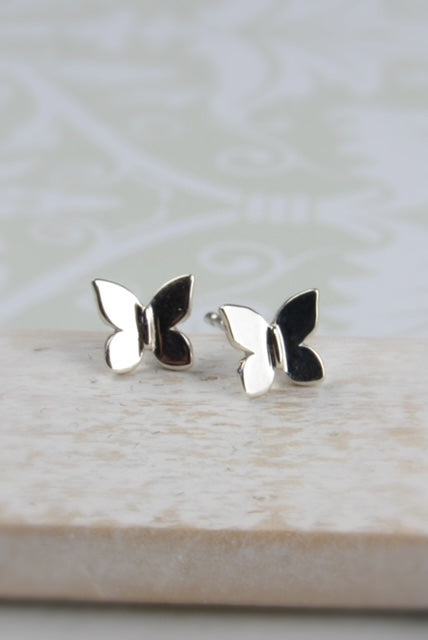 Butterfly-shaped silver earrings on a light wooden surface 