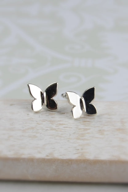 Butterfly-shaped silver earrings on a light wooden surface 