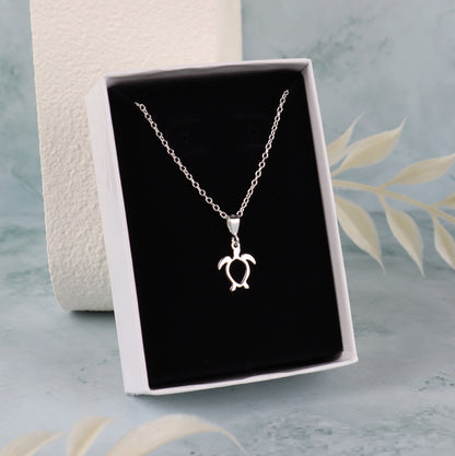 Silver turtle pendant necklace in a black box on a light blue background