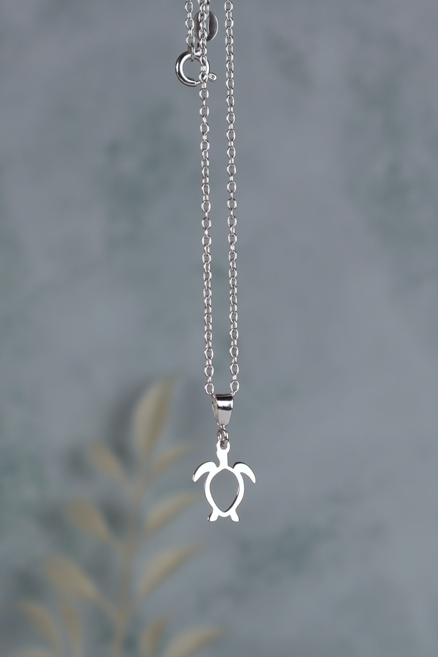sterling silver sea turtle necklace for women in front of a blue background