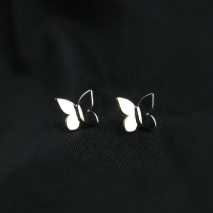 Butterfly-shaped silver earrings on a black background