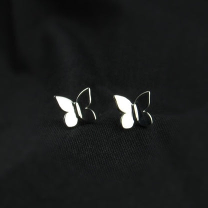 Butterfly-shaped silver earrings on a black background