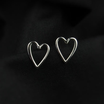 Heart-shaped silver earrings on a dark background