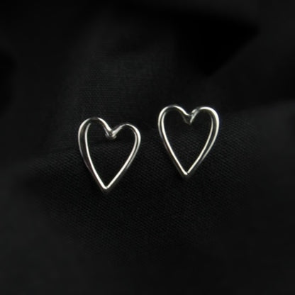 Heart-shaped silver earrings on a dark background