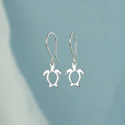 Silver turtle earrings on a light blue background